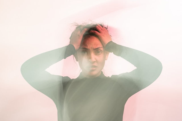 Woman with hands on her head, photo distorted as if in a fog