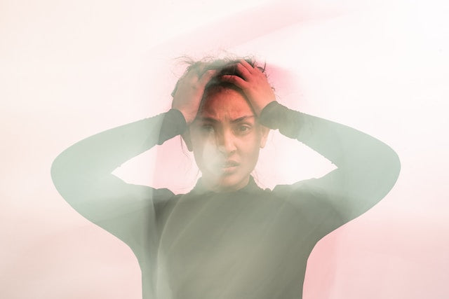 Woman with hands on her head, photo distorted as if in a fog