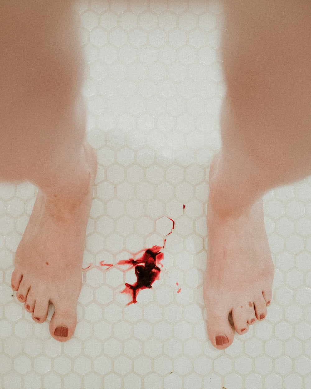 dark red menstrual blood on bathroom floor tiles