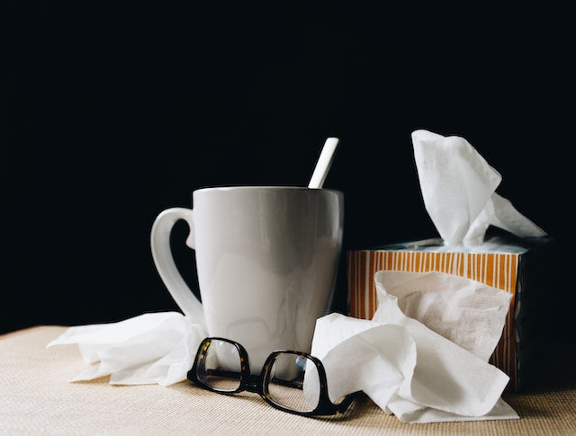 mug of tea, tissue box, and used tissues scattered