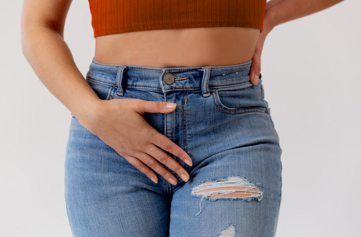 woman holding hand over her lower abdomen, as if in pain