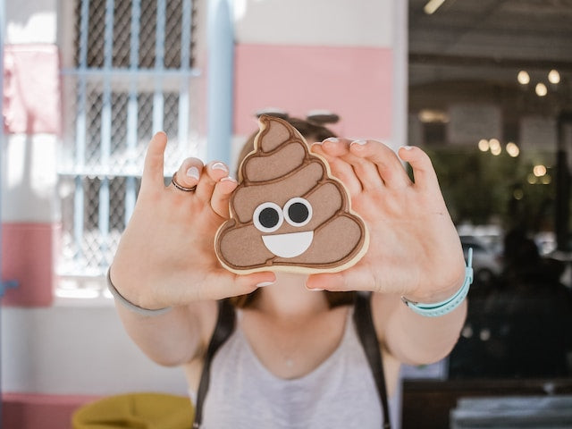 girl holding poop emoji cookie in front of her face